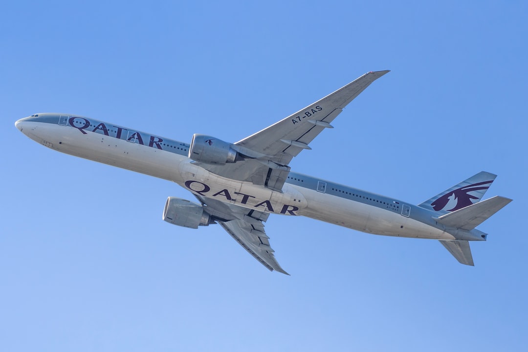 Qatar airways airplane ascending against a clear blue sky